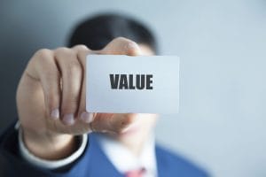 Businessperson holding a card with the word VALUE, representing the question ‘Who Carries Out the Valuation’ in property assessment.